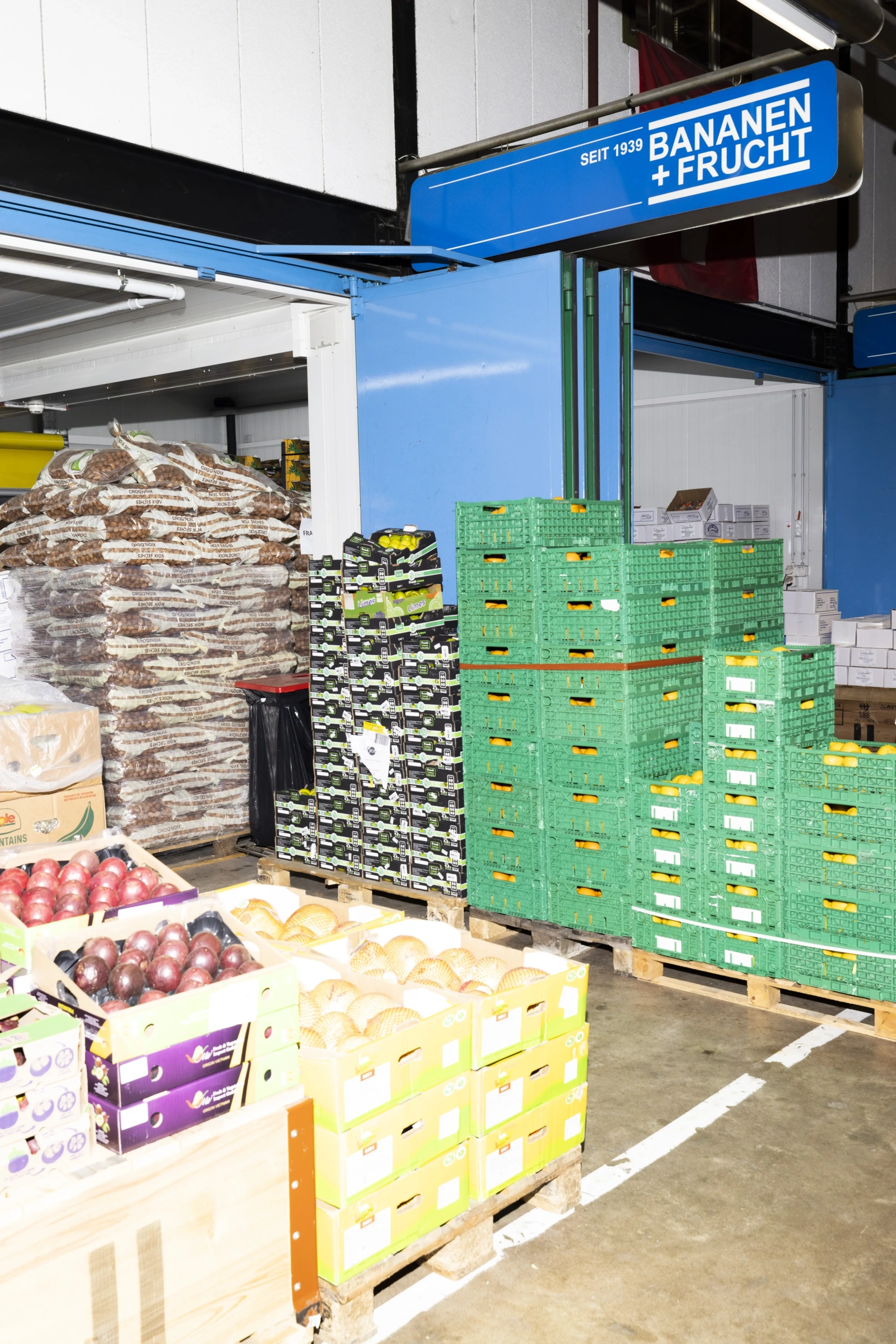 Interior of the Bananen + Frucht AG warehouse in Zurich with fresh fruit, crates and the new company signage.